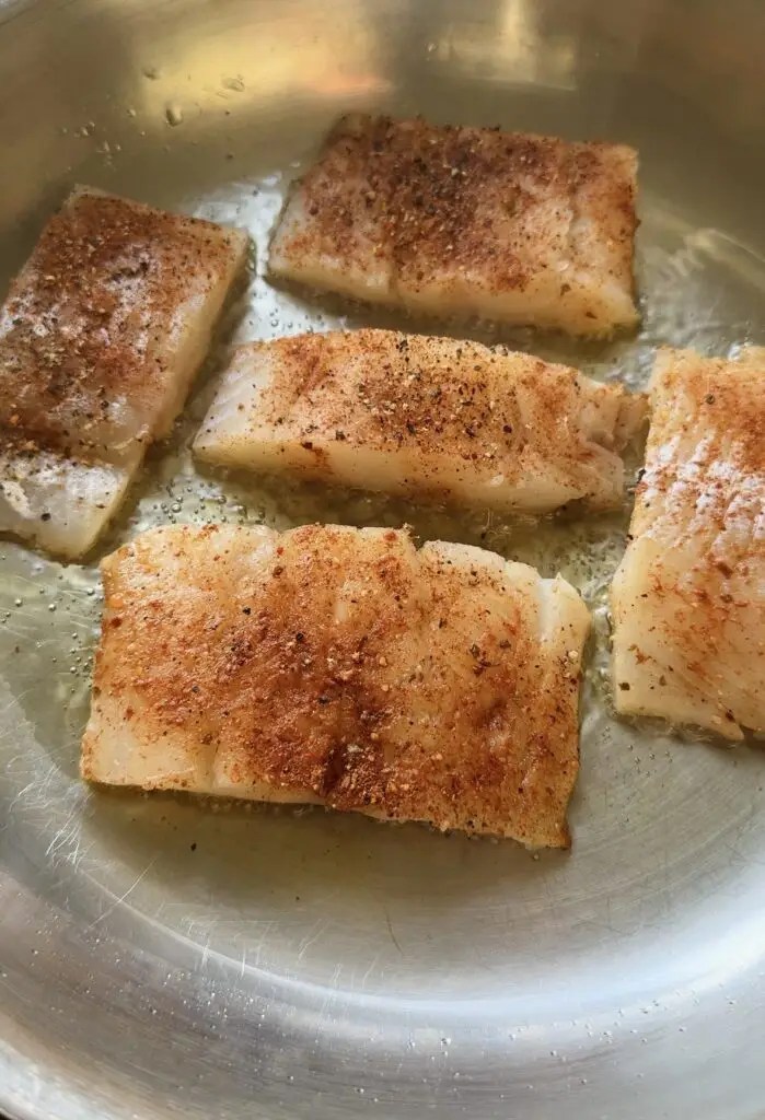 saute pan with fish filets cooking in it