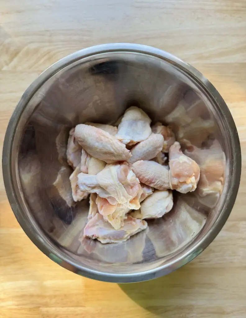 Raw chicken wings in a mixing bowl.