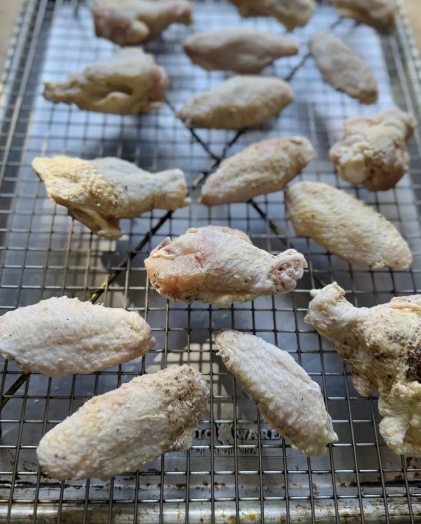 Chicken wings on a sheet pan lined with a wire rack.