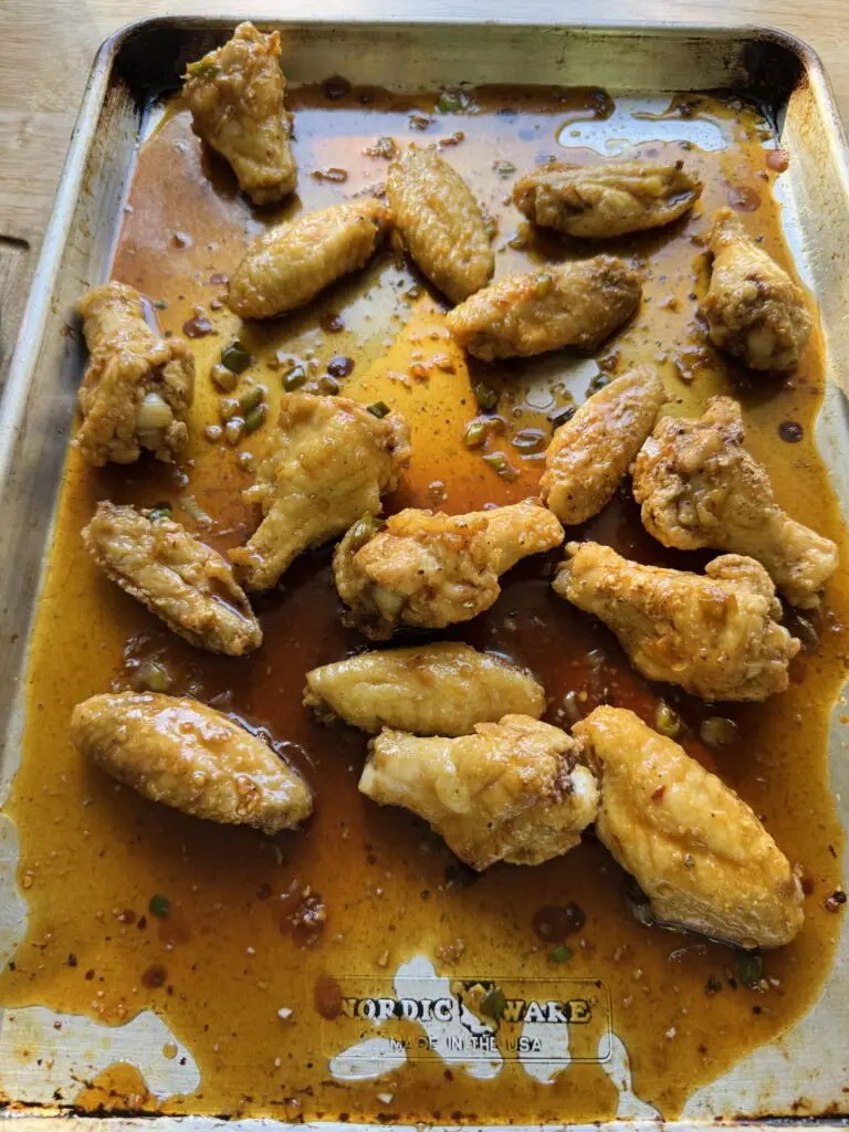 Soy garlic chicken wings with sauce on a sheet pan.