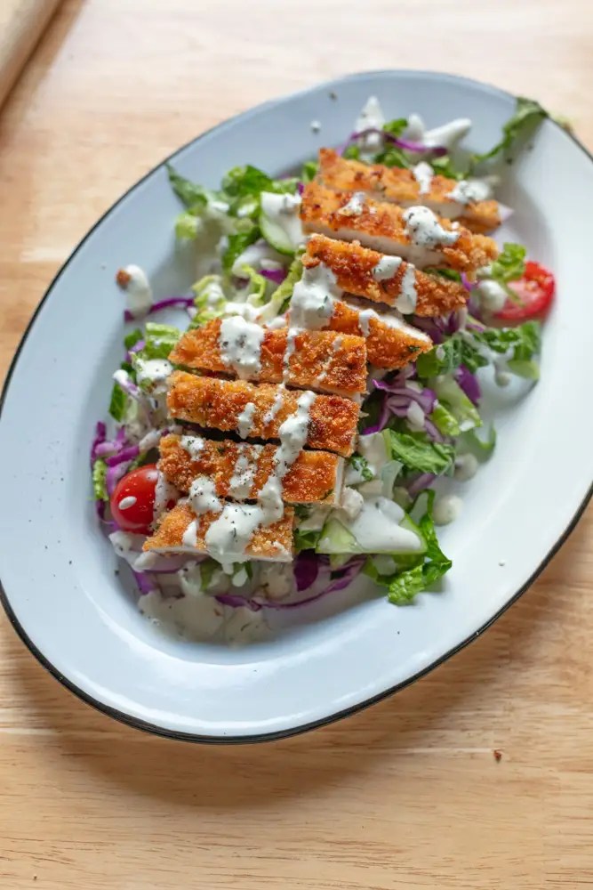 Chicken schnitzel served on top of bed of salad.