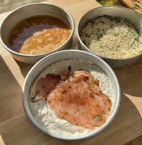 Breading the chicken fillet in flour, egg, and breadcrumbs.