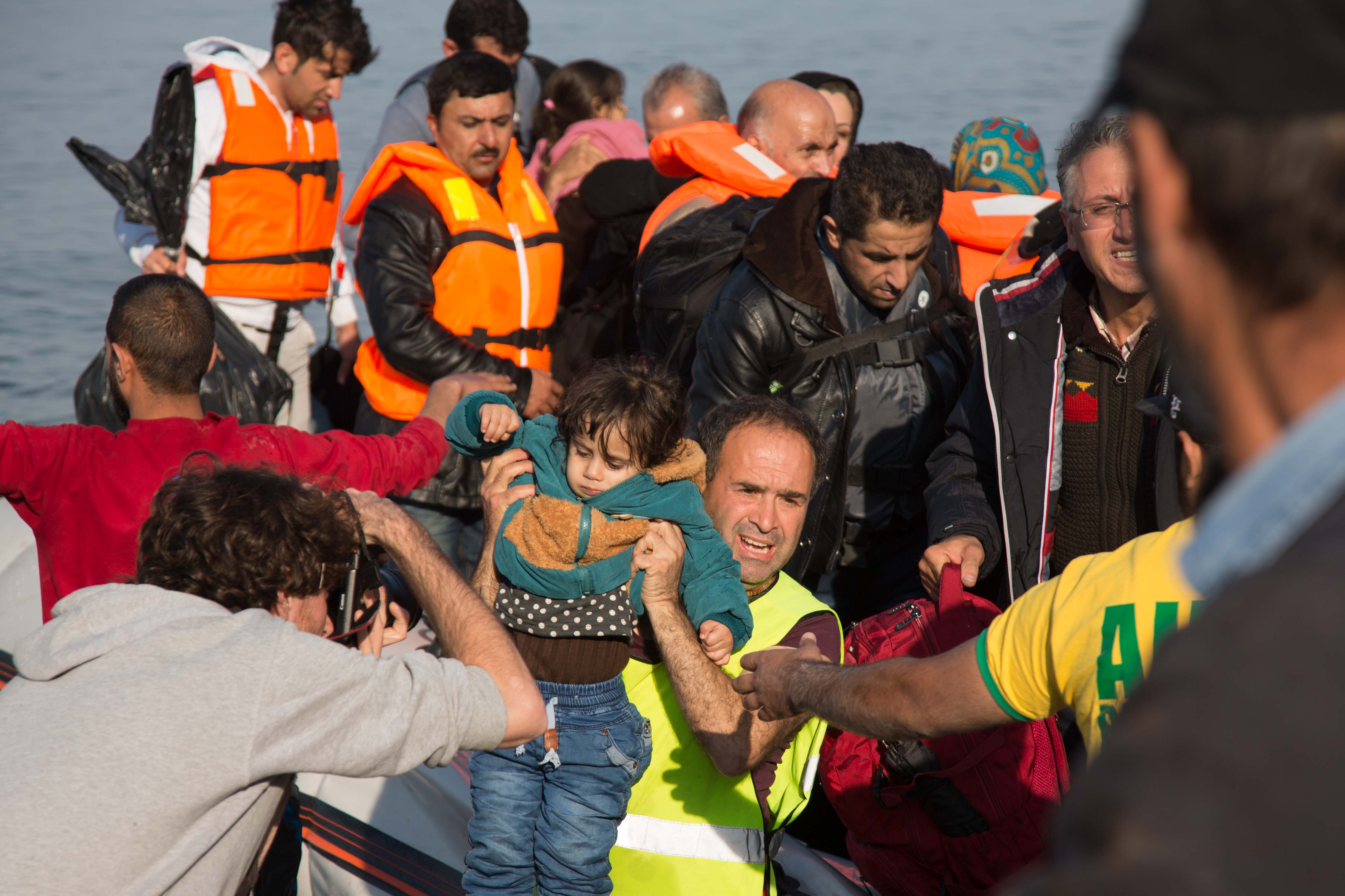 Children are picked out of the boats first and passed on shore for a quick check up and wrapped in blankets.