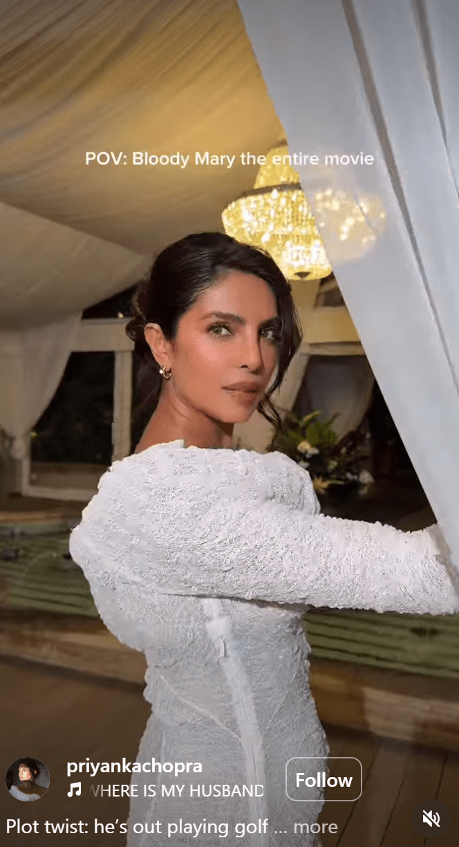 A woman in a white lace dress poses with a contemplative expression, standing near a chandelier in a softly lit indoor setting, with text overlay referencing a movie.