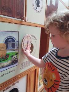 Photo of a toddler sliding a flap on a wall display about Greyfriar's Bobby