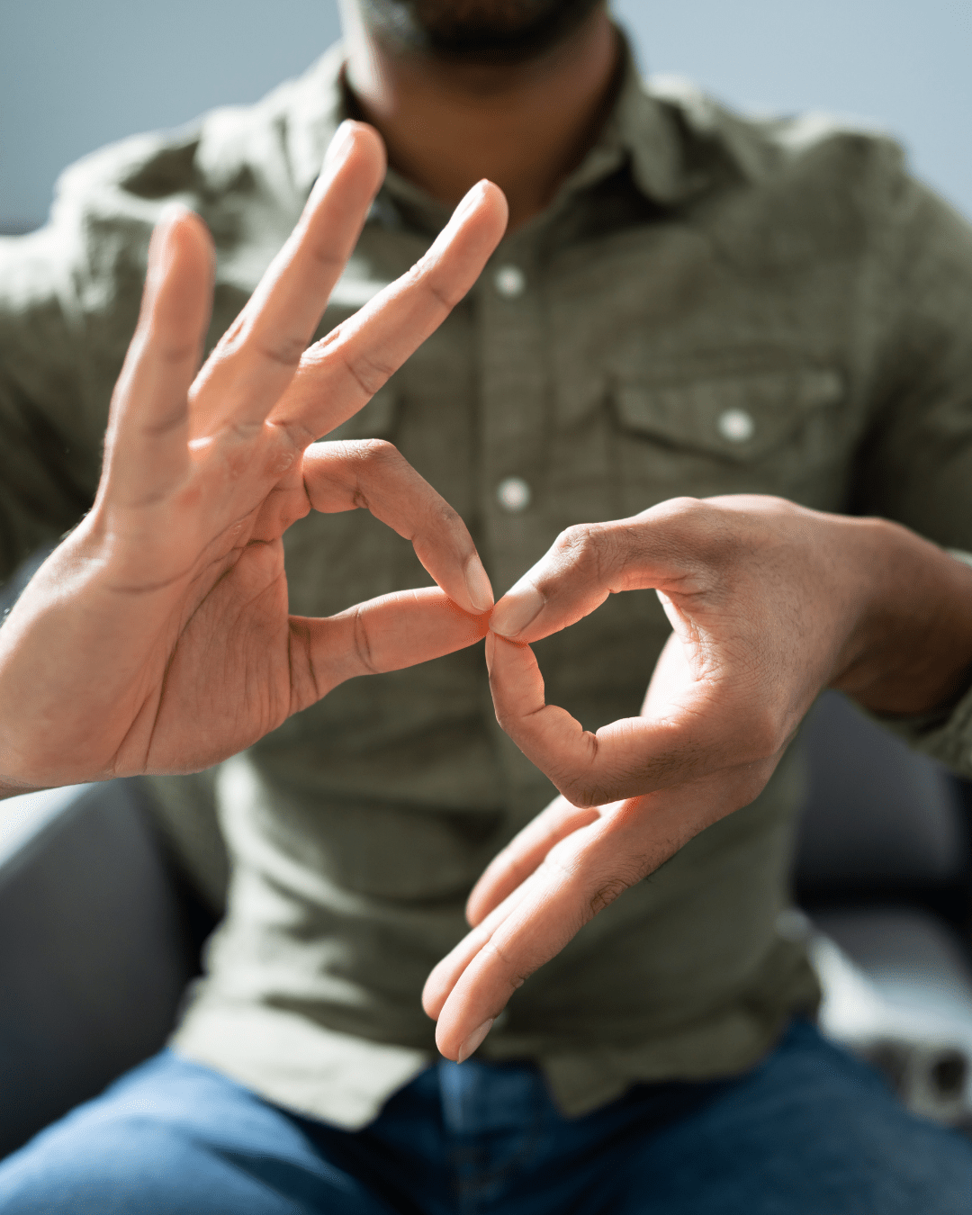 Close-up of hands forming a circular shape with fingers during a sign language gesture.