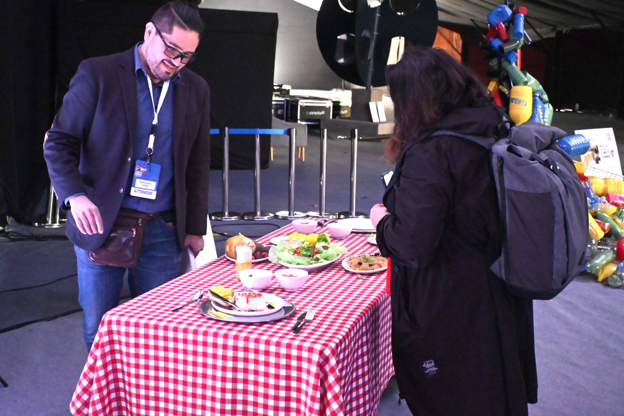 Ricardo Núñez-Morales, an artist from The Future School (left), guides an exhibition attendee through the innovative fusion of plastics and food. Photo by Fredrick Mugira