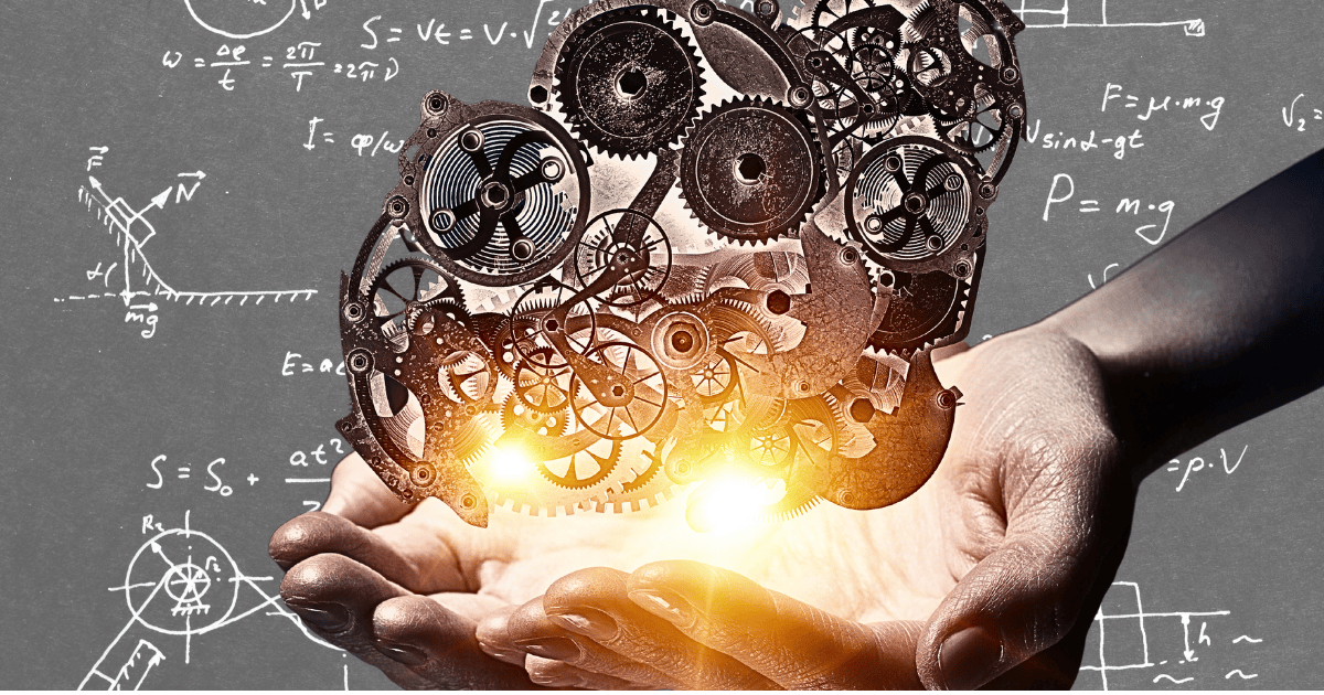 hand holding a model of gears to with a regression model on a chalkboard in the background