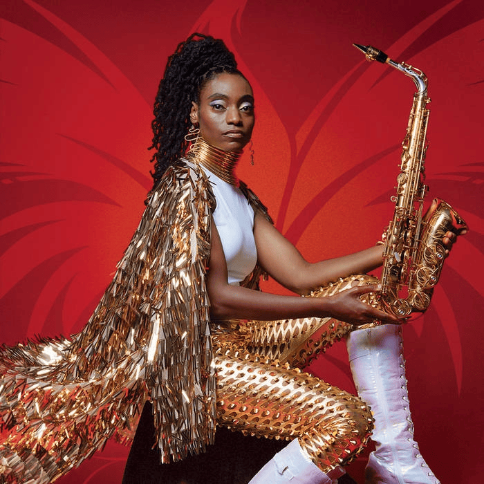 Woman in a gold sequined outfit holding a saxophone against a red backdrop, embodying bold musical style.