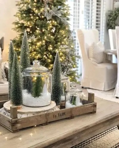 Festive Christmas coffee table decor featuring mini Christmas trees and a glass jar display, adding a cozy and elegant holiday touch to your living room setup.