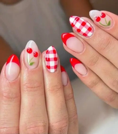 Red gingham accent nails paired with red French tips and tiny cherry nail art for a fun summer picnic-inspired manicure.