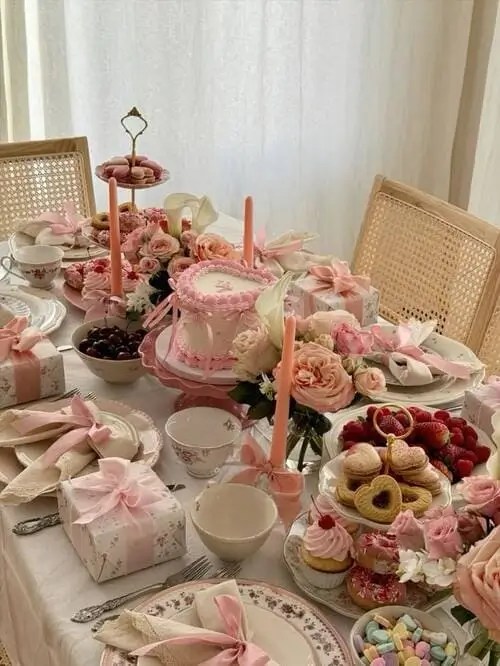 A coquette-theme 19th birthday party brunch with pink bows everywhere, heart-shaped cookies, strawberries, cherries, pastries, finger foods, and fresh flowers.