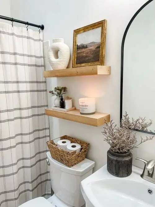 To decorate above the toilet, try floating shelves. Decorate them with chic bathroom decor like small bathroom vase and wicker basket for toilet paper.