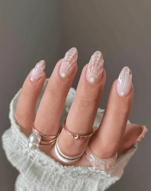 Close-up of neutral coastal seashell nails featuring soft taupe, sand tones, sculpted water, and pearly shimmer with elegant shell-inspired detailing.