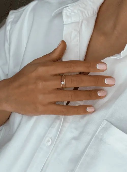 Reverse French manicure with curved color accent at the base of nude nails—modern summer nail design trend for 2025.