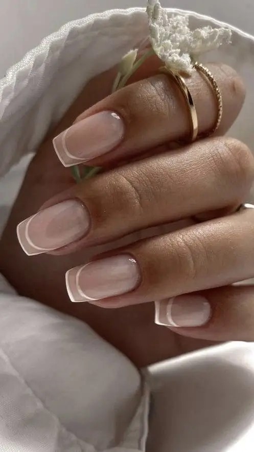 Nude nails with fine white outline along the tip for a minimalist, modern French manicure - clean and edgy nail design ideal for summer sophistication.