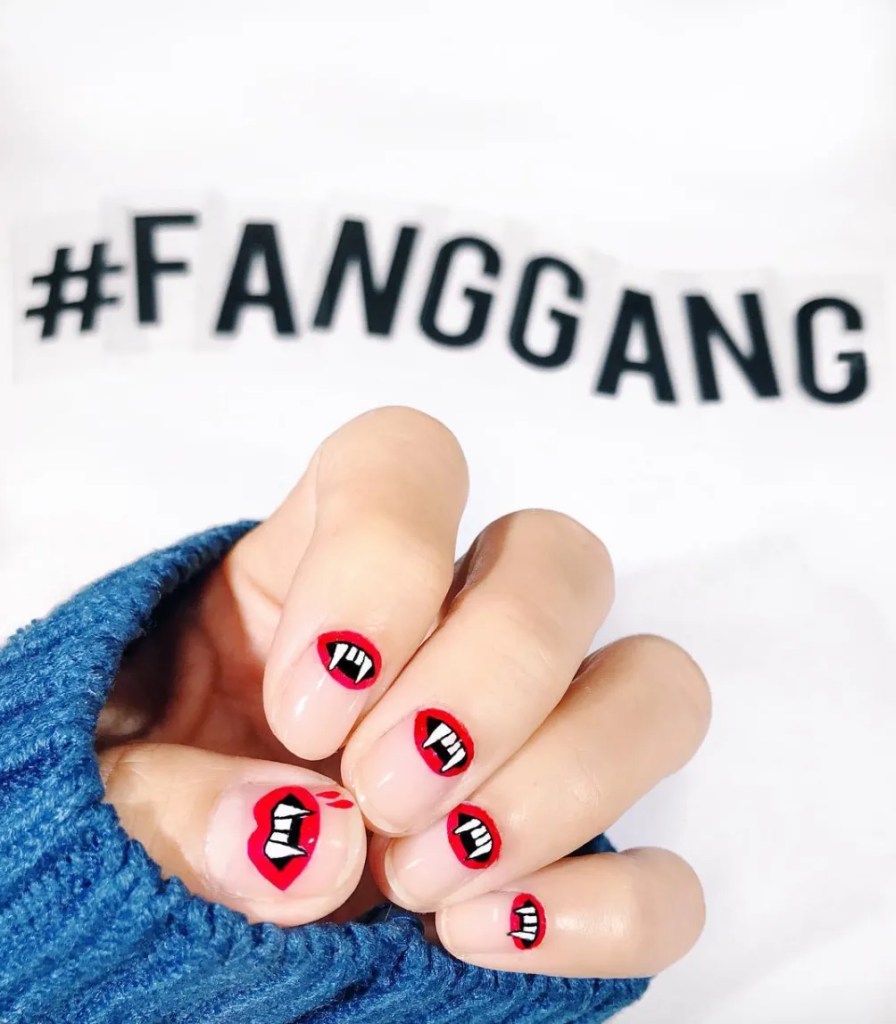 short Halloween nails with red lips and vampire fang nail art, playful vampire manicure idea