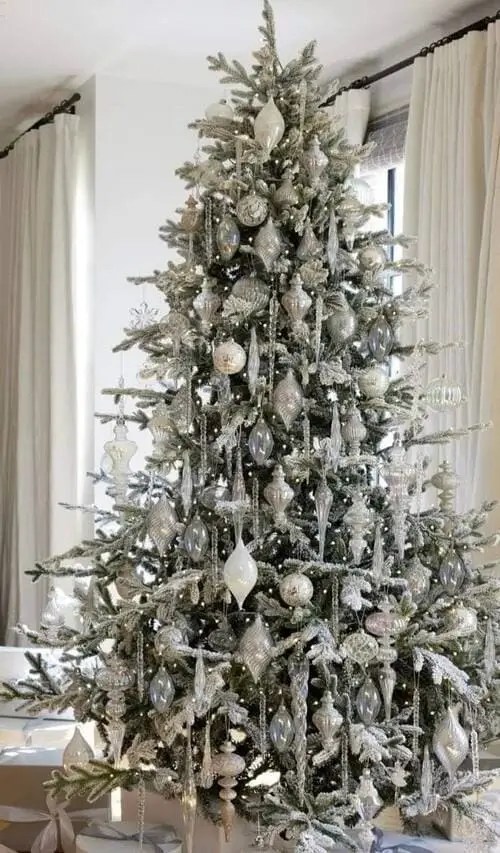 Elegant glass ornament Christmas tree with frosted branches, shimmering icicle ornaments, and silver baubles for a winter wonderland holiday look.
