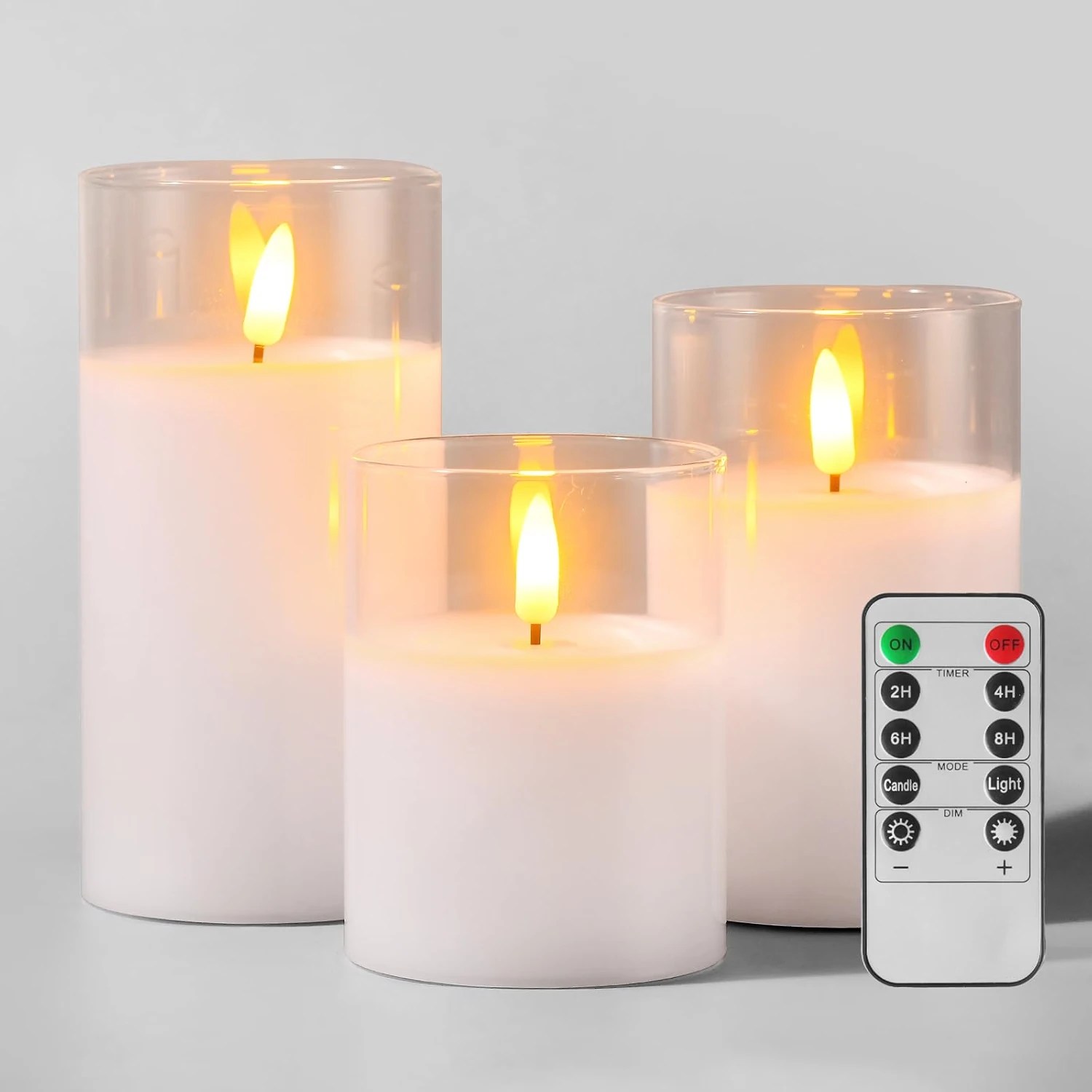 Set of three flameless pillar candles in clear glass holders with remote control and timer settings
