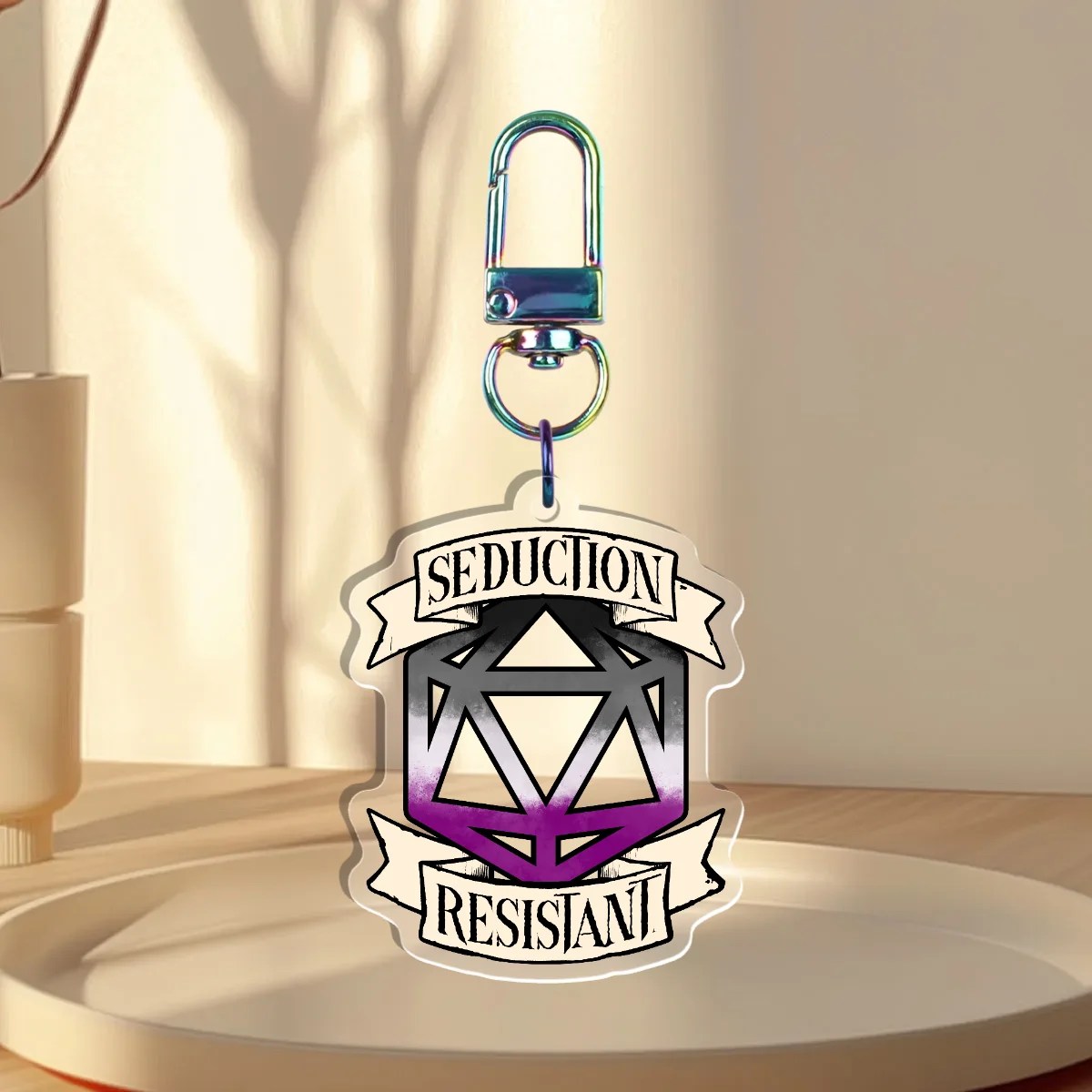 Keychain Design – D20 die filled with the asexual flag with a banner that states “Seduction Resistant”, back with is clear without iridescent holographic overlay