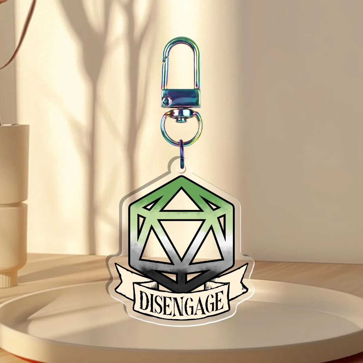 Keychain Design – D20 die filled with the aromantic flag with a banner that states “Disengage”, back with is clear without iridescent holographic overlay