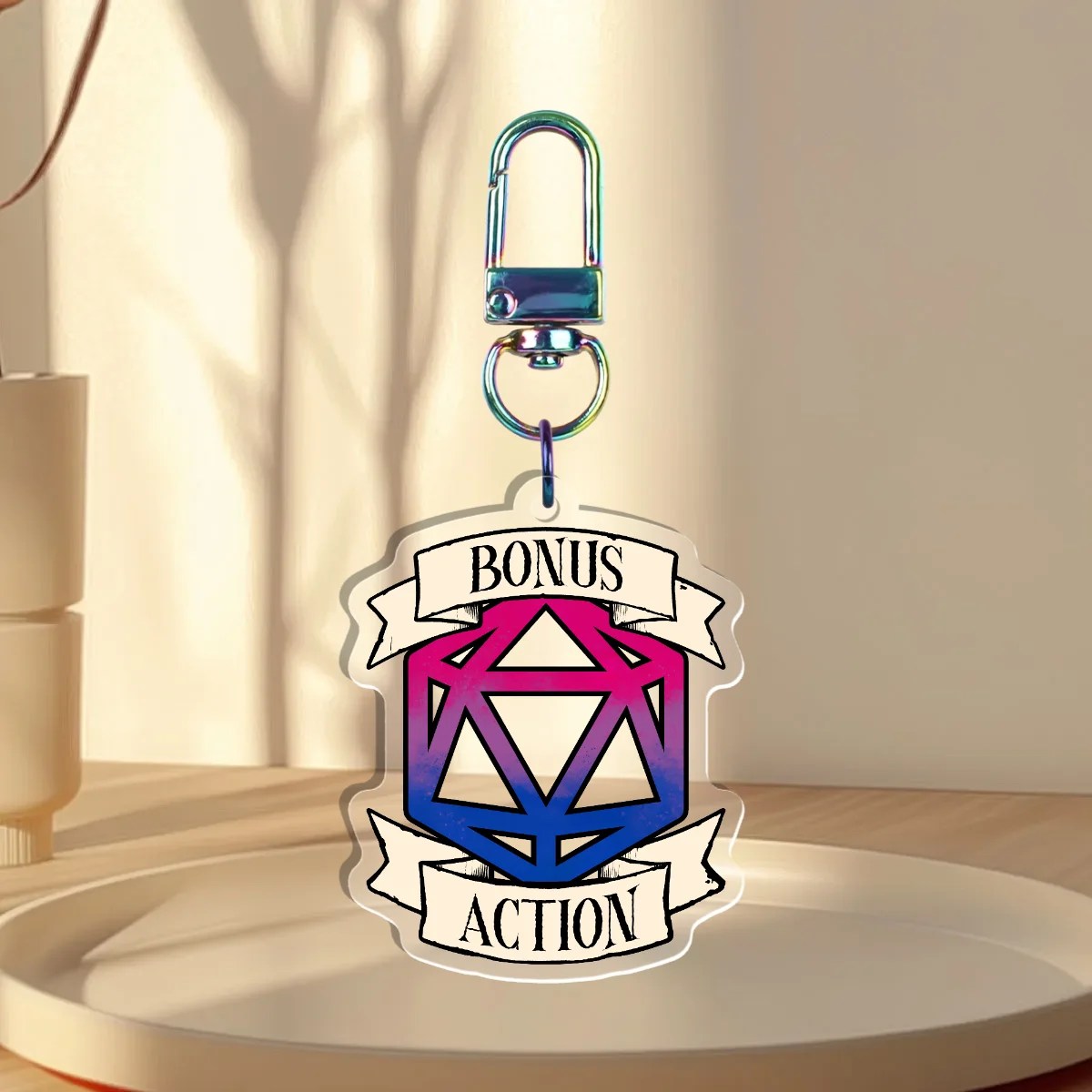 Keychain Design – D20 die filled with the bisexual flag with a banner that states “Bonus Action”, back with is clear without iridescent holographic overlay