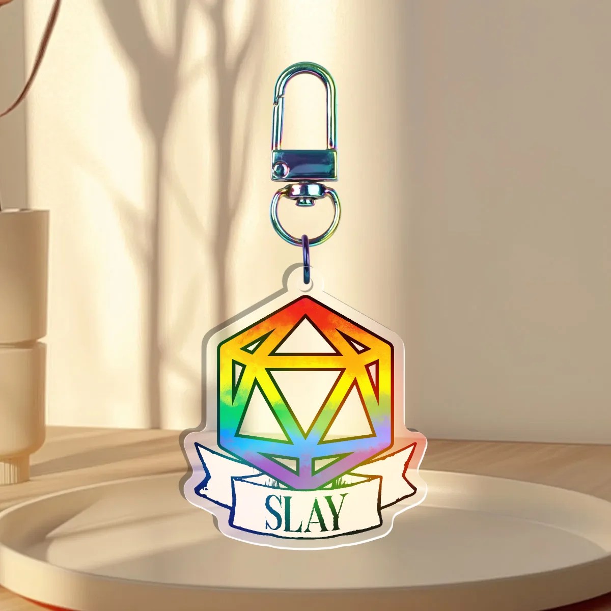 Keychain Design – D20 die filled with rainbow pride flag with a banner that states “slay”, front with a iridescent holographic overlay
