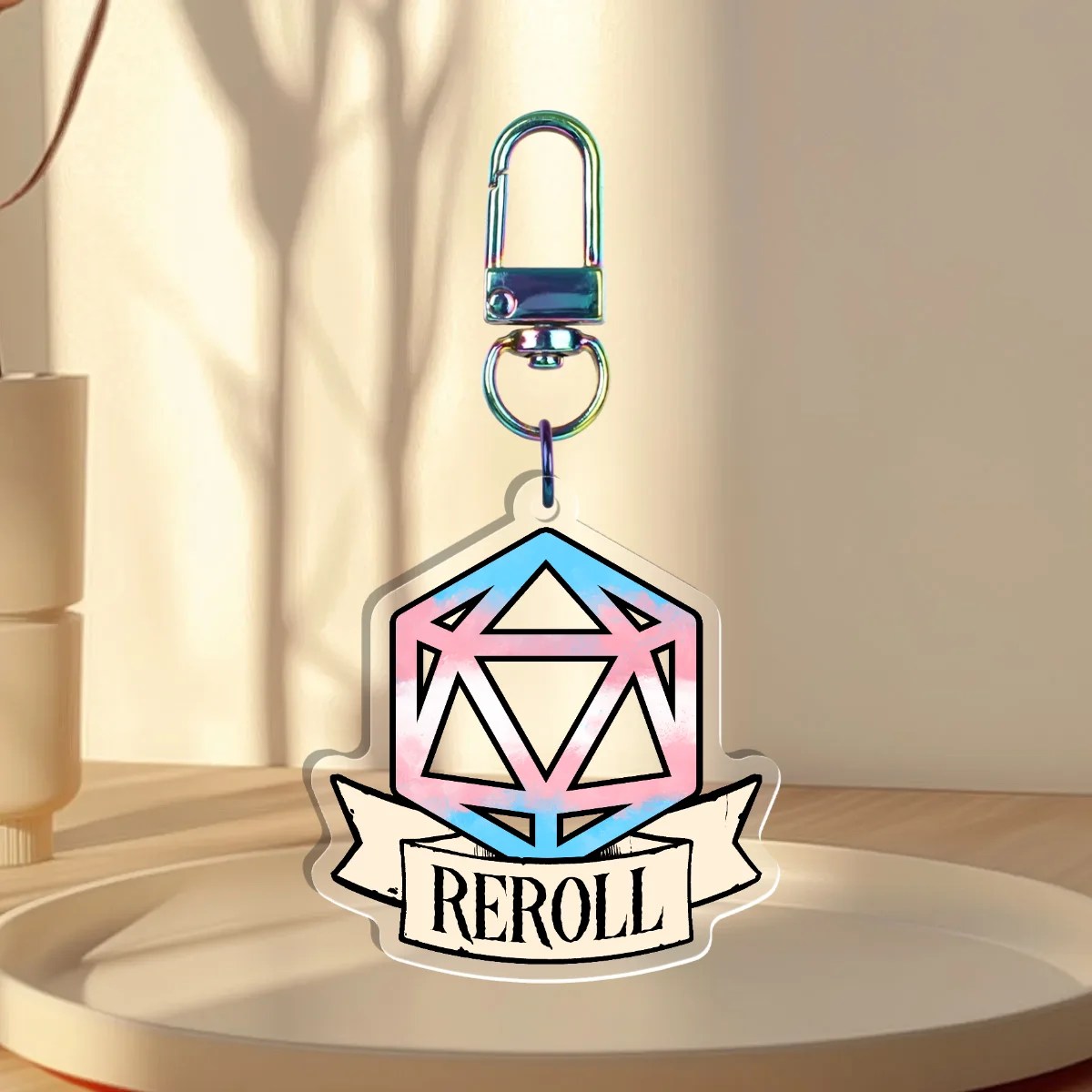 Keychain Design – D20 die filled with transgender pride flag with a banner that states “reroll”, back is clear without iridescent holographic overlay