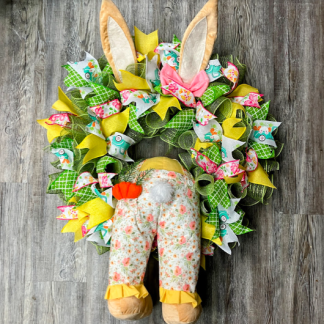 Spring bunny bottom ruffle ribbon wreath with green mesh, colorful Easter ribbon, floppy bunny ears, and floral bunny tail centerpiece
