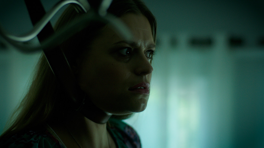 Woman with a concerned expression in dim, moody lighting.