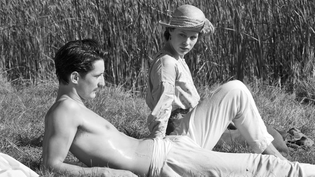 Black and white photo of a man and woman relaxing outdoors in vintage style.