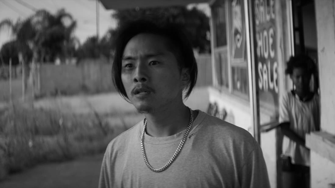 Black and white portrait of a young man outdoors with a thoughtful expression.