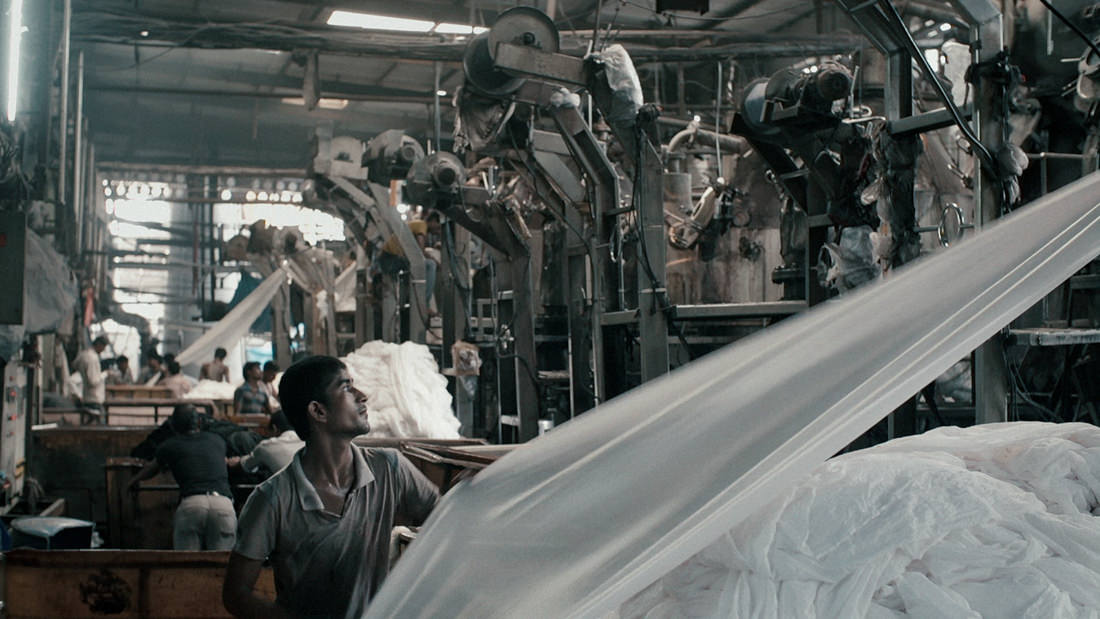Man inspects machinery in an industrial factory setting.
