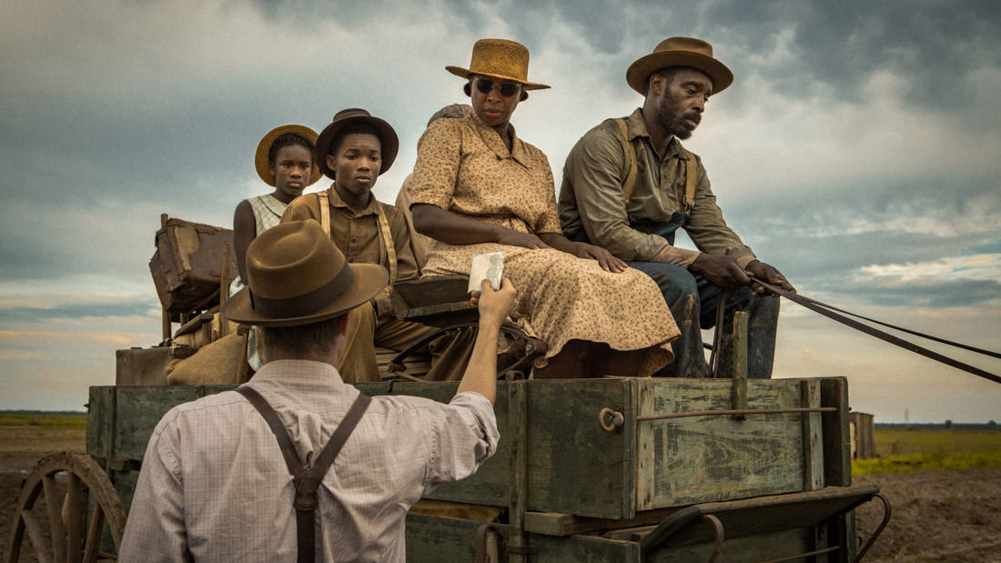 A vintage scene of a family dressed in early 20th-century attire on a wooden cart.