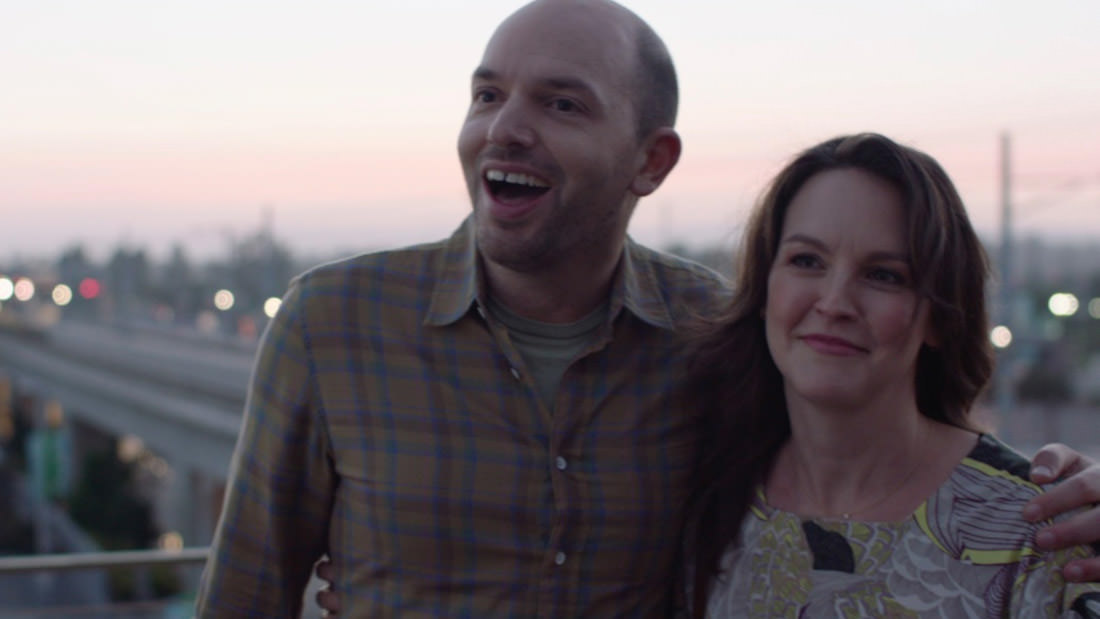 Two people smiling outdoors during sunset.