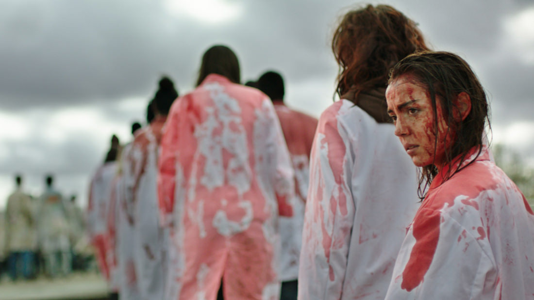 People wearing blood-stained clothing, possibly in a protest or performance.