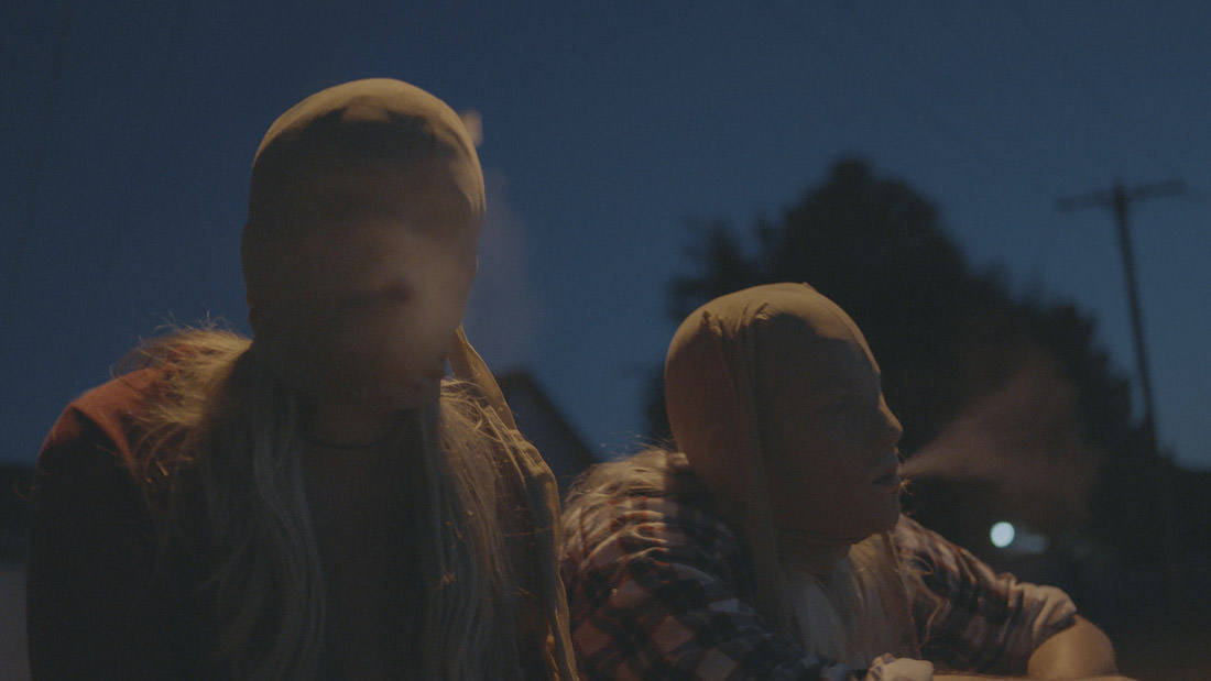 Two people in hoodies standing outdoors at dusk.