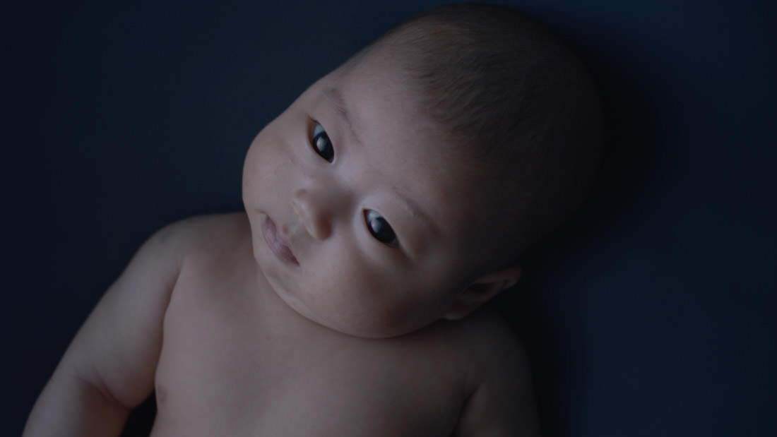Close-up of a curious baby looking to the side in soft lighting.