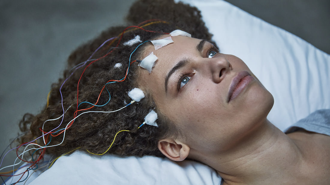 Person with electrodes attached to their head, lying down.
