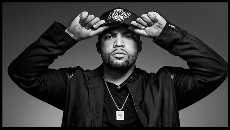 Man in a black hoodie and cap posing confidently.