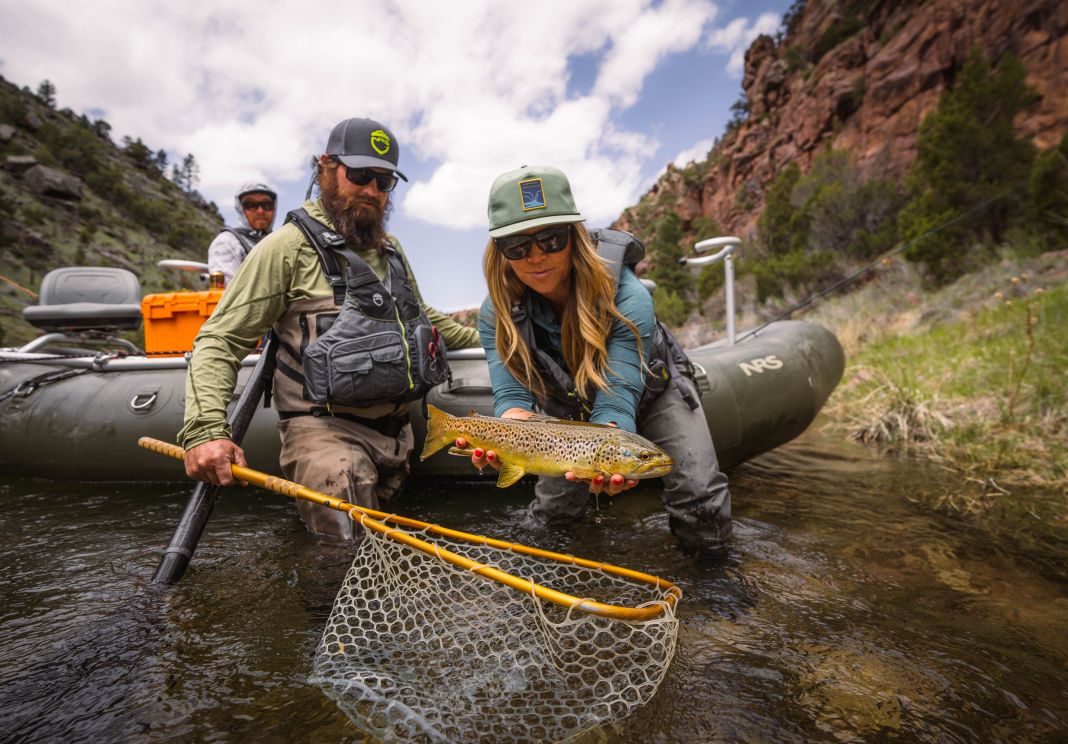 holding a trout infront of a raft