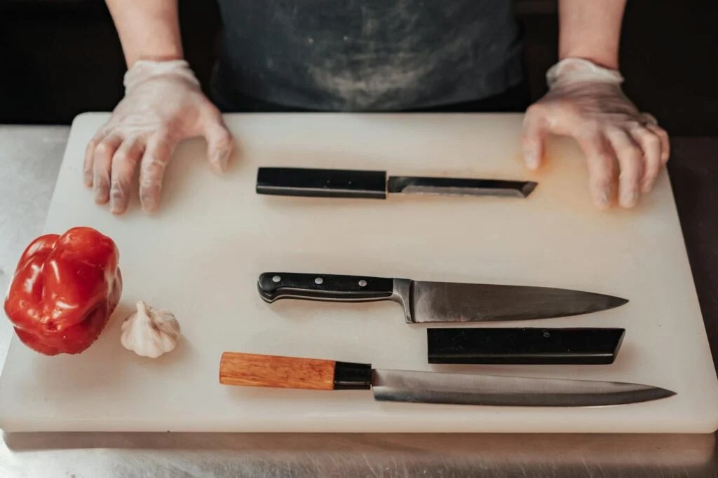 Delicious Greek Souvlaki Platter Recipe In 2 Hours 9 Gloved hands preparing to chop with knives on a cutting board next to vegetables in a kitchen scene.