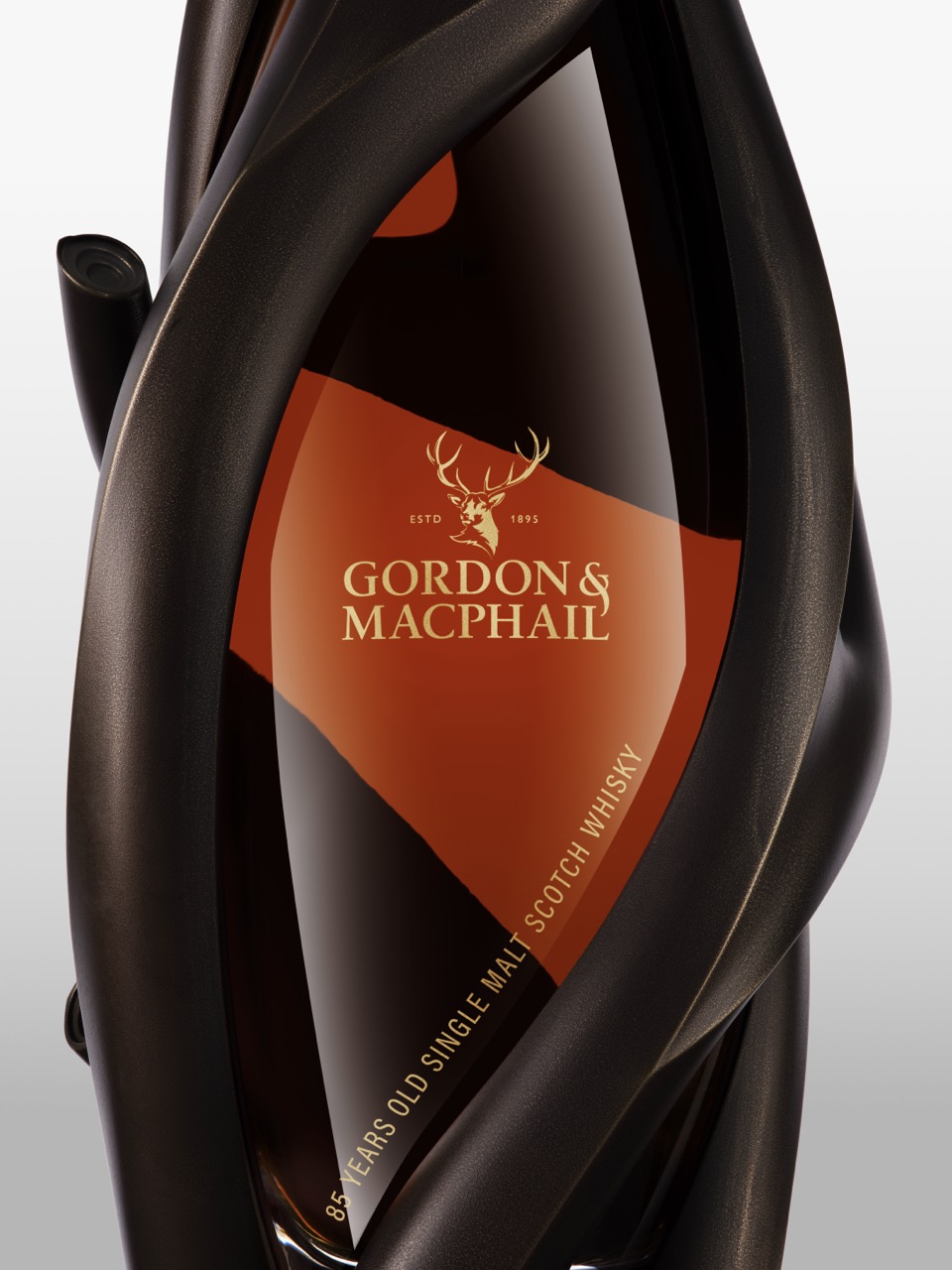 The Forge - Close-up of a Gordon & MacPhail 64-year-old single malt Scotch whisky bottle, encased in a sculpted dark metal frame with the brand logo and text visible on the front.