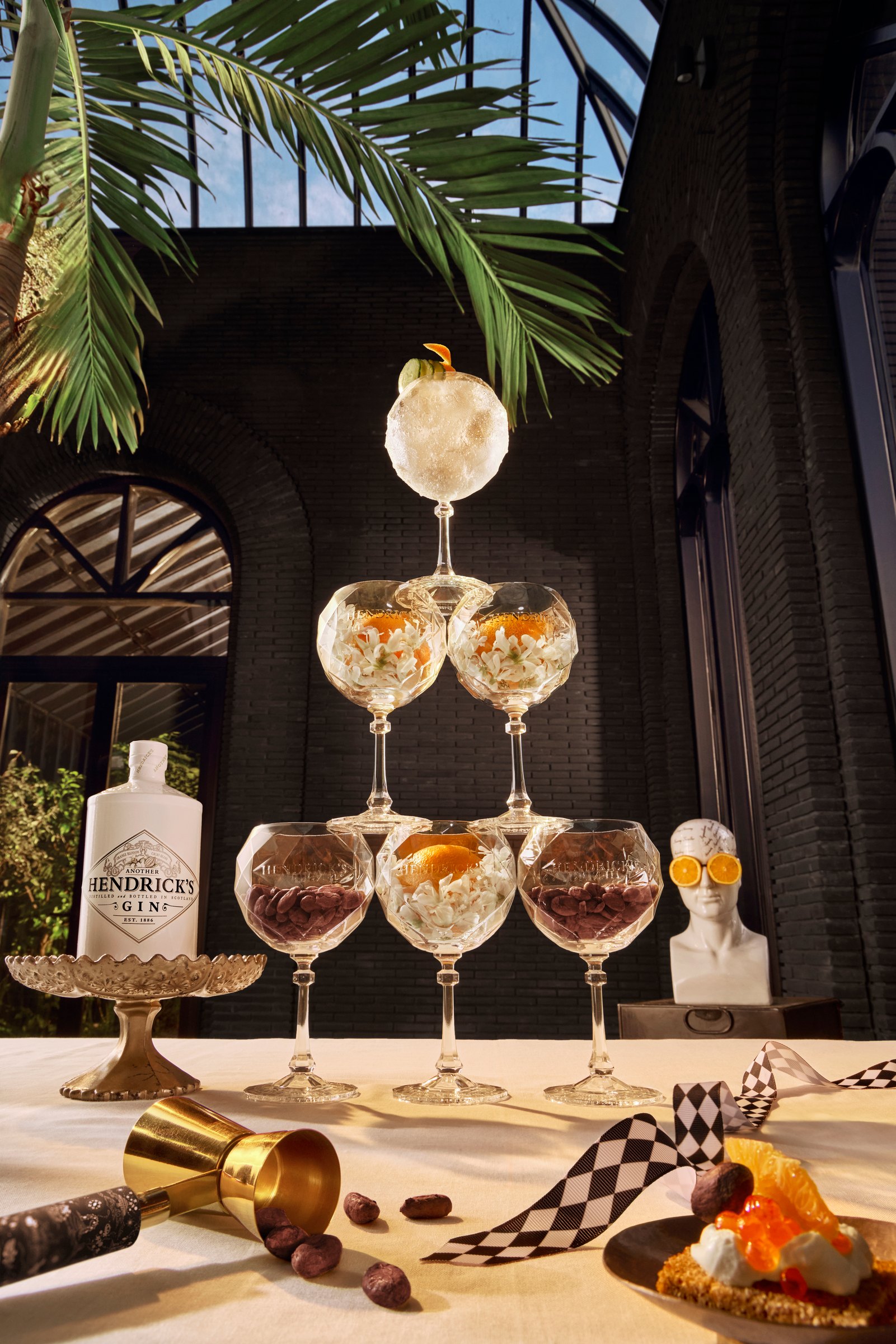 The Forge - A tower of cocktail glasses on a table with Another Hendrick's gin and a palm frond above.