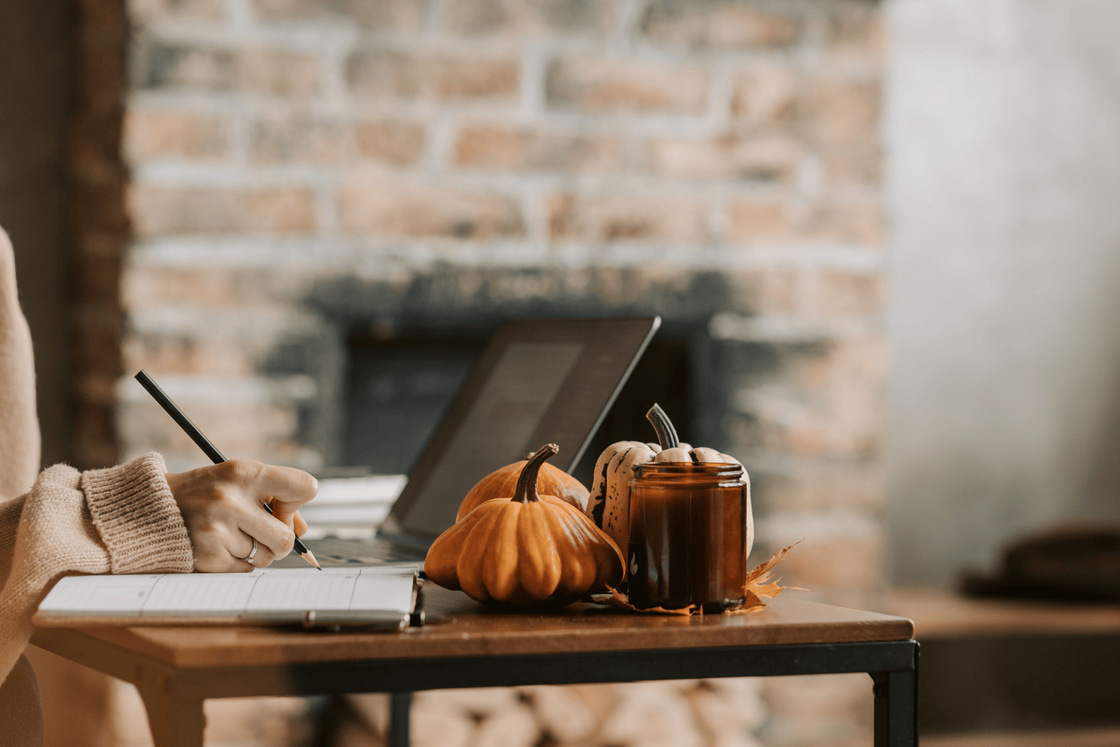 Woman writing in a notebook at home during autumn, creating space for reflection and planning.