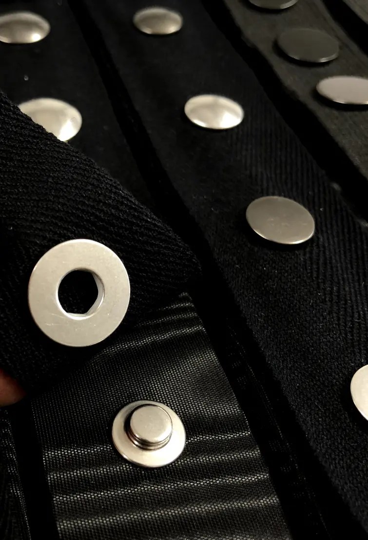 “Detalle de chaqueta negra con apliques metálicos circulares – producción de ropa personalizada en España | The Good Decisions”