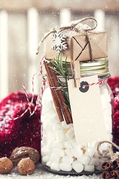A mason jar full of marshmallows and a small wrapped gift make for the perfect sustainable stocking stuffers under $25.