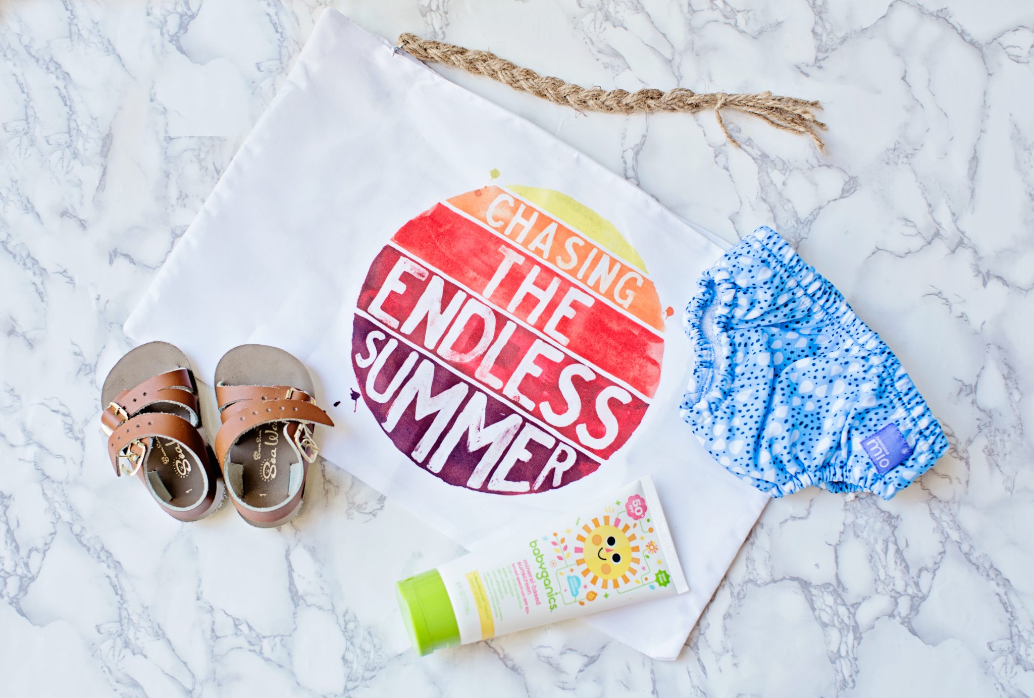 baby sandles, sun tan lotion and sunscreen with bag saying ' chasing the endless summer'