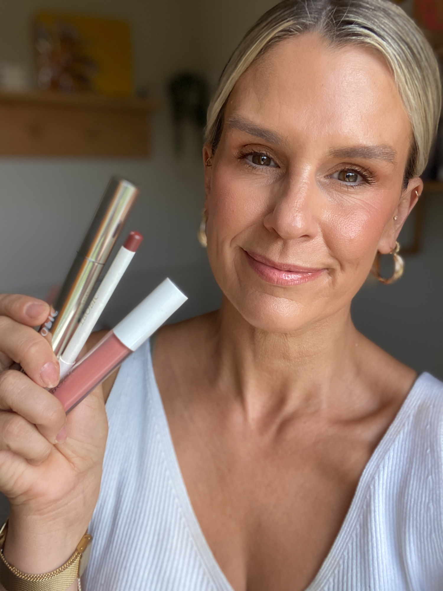 lady holding makeup products with glowing skin