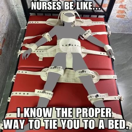 A mannequin tied to a twin bed with various white restraints for all over the body.